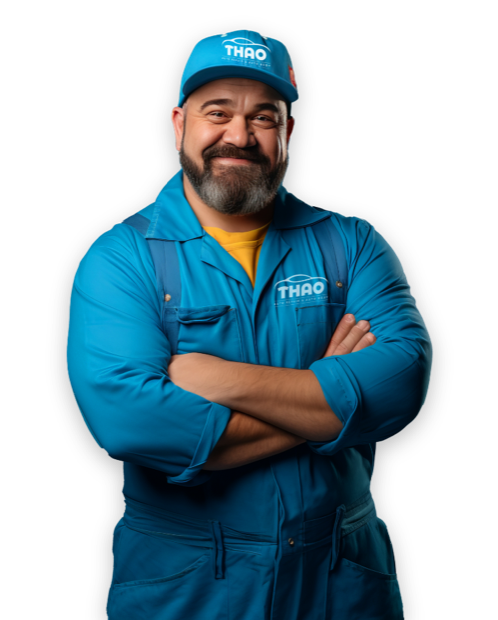 A technician in blue coveralls, arms folded