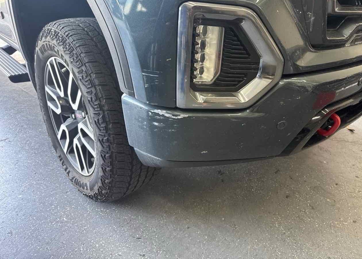 Scraped and scuffed front bumper corner on a pickup truck