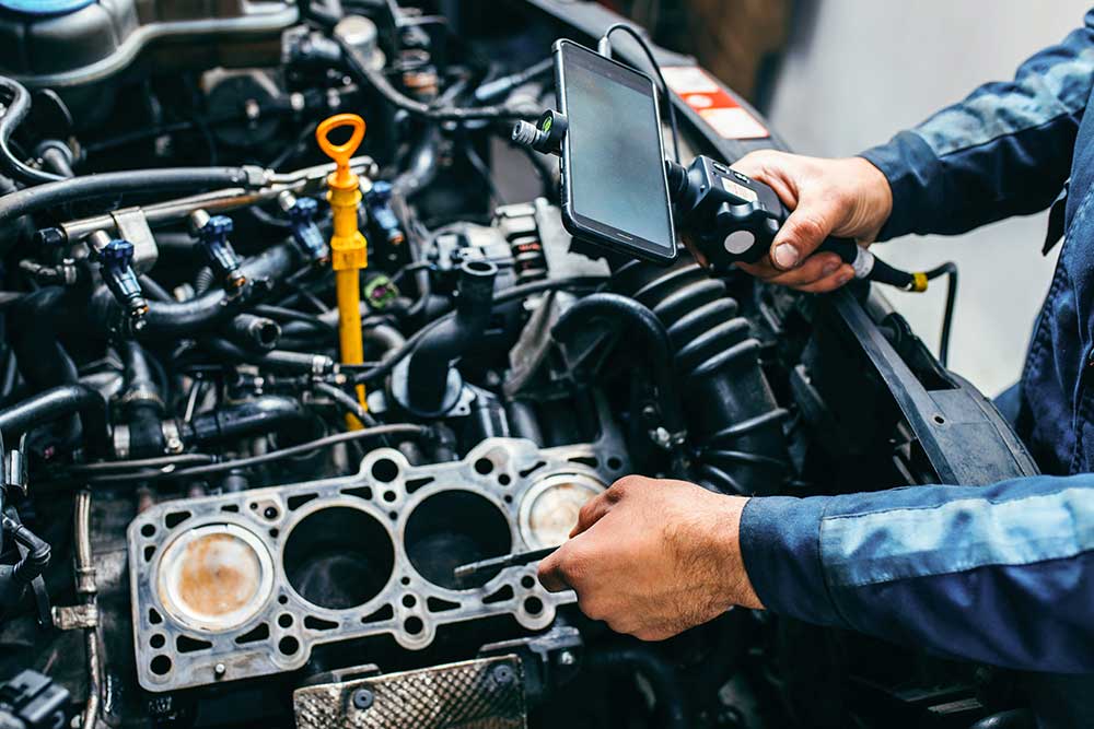 A cylinder head gasket held over an engine block during a rebuild