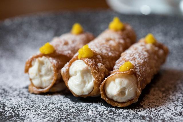 Three cannoli dusted with icing sugar.