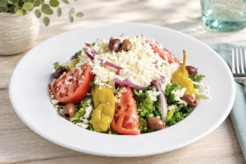 A Greek salad heaped with feta, tomato, red onion, olives and pepperoncini.