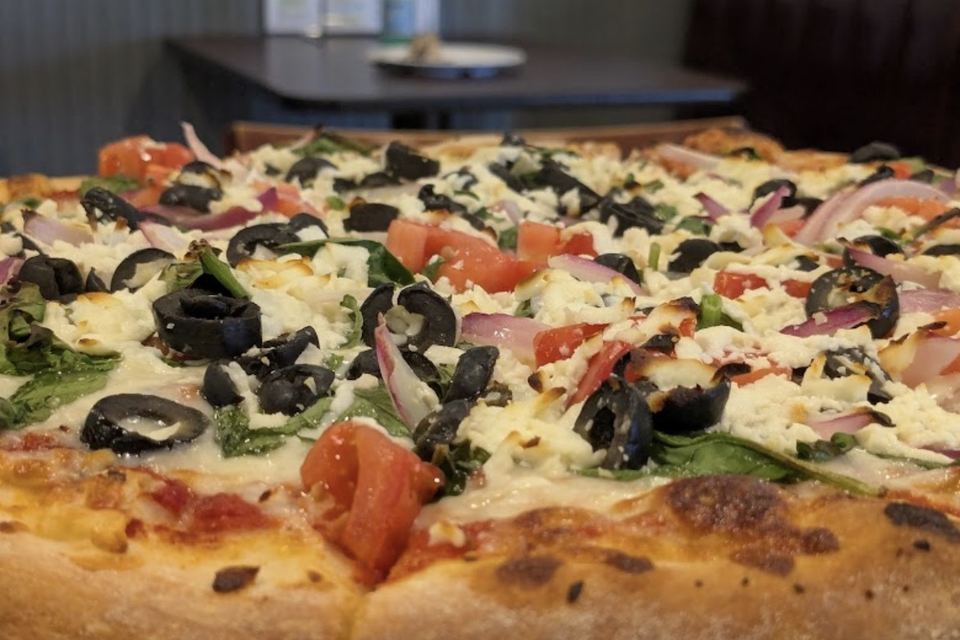 The Mediterranean Calm, close up at the crust: feta, spinach, black olives, tomato and red onion.